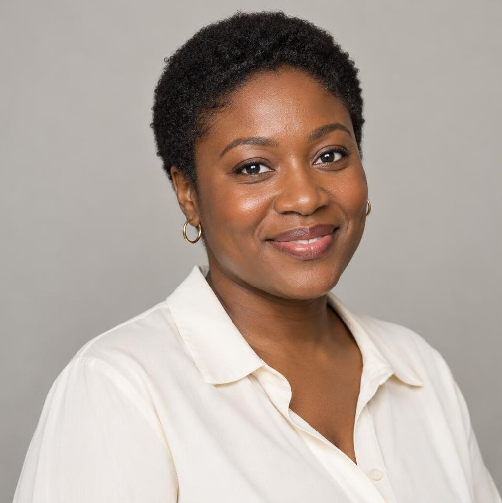 Portrait of a Black British woman producer smiling in a light blouse